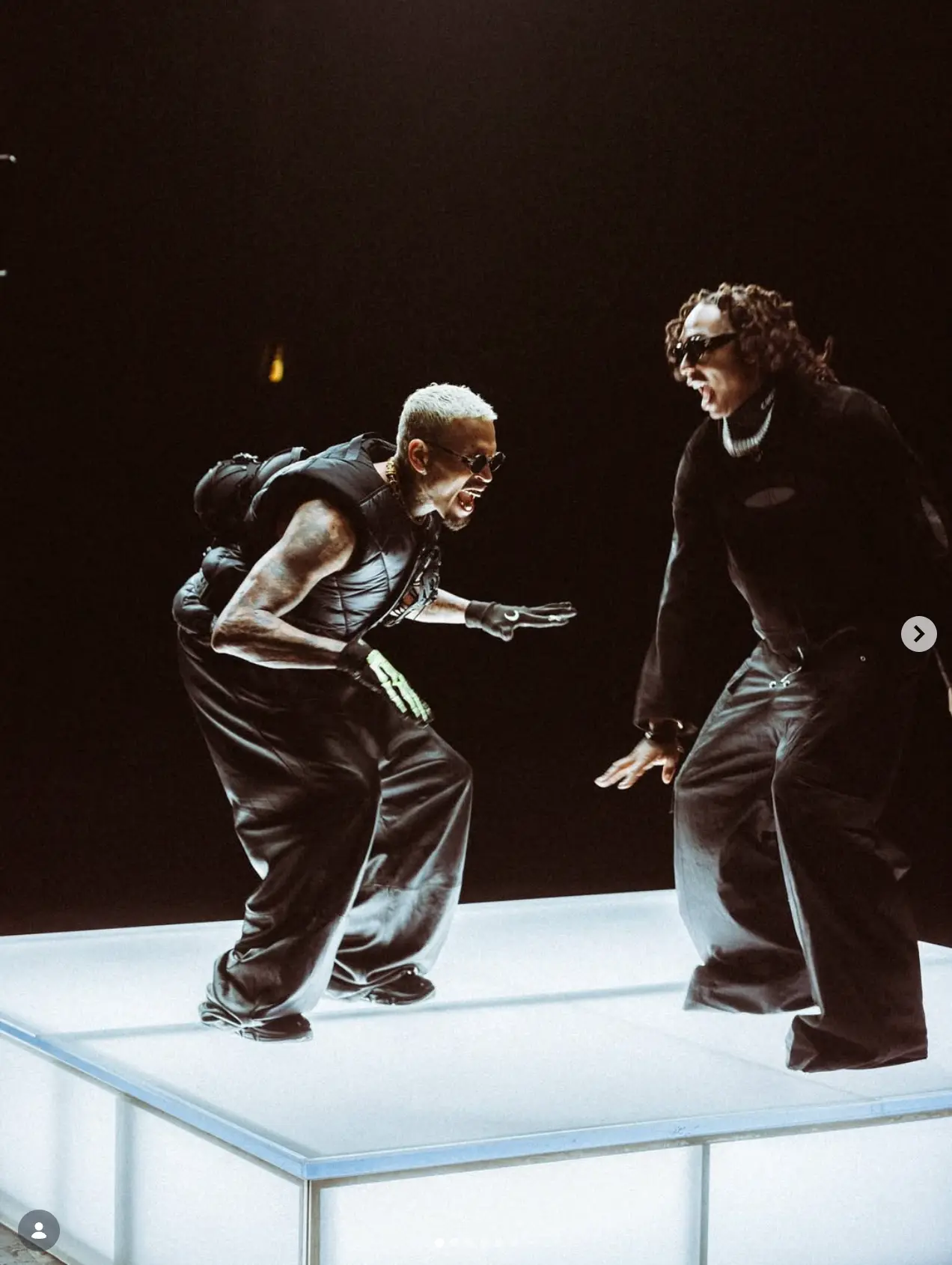 Two performers on a lit stage platform
